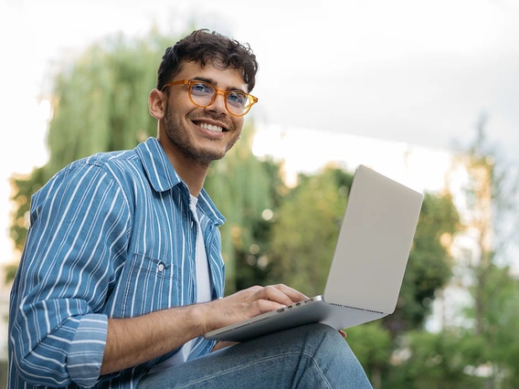 Male student on laptop outside